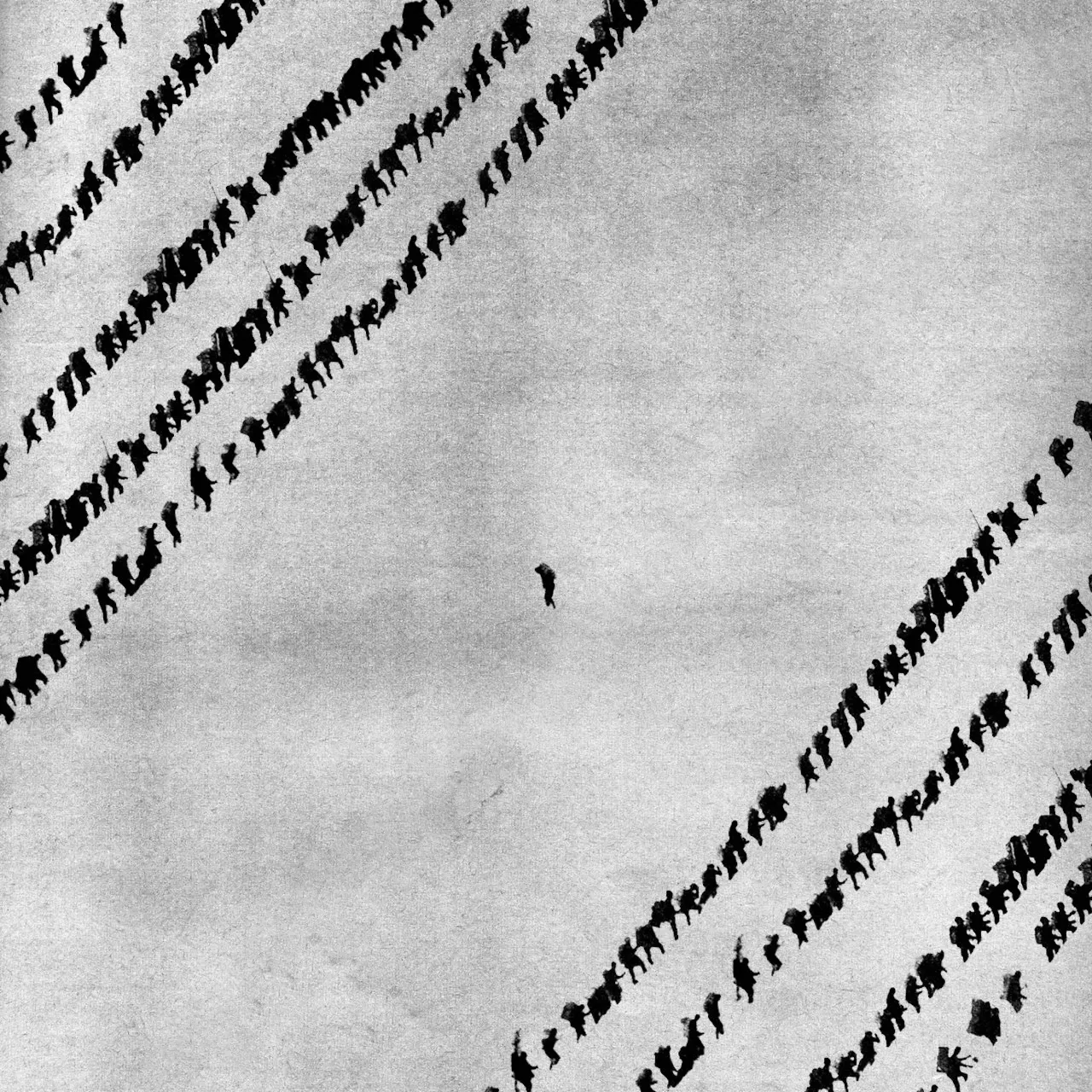Man walking back down a mountain. Lines of people walking the other way.